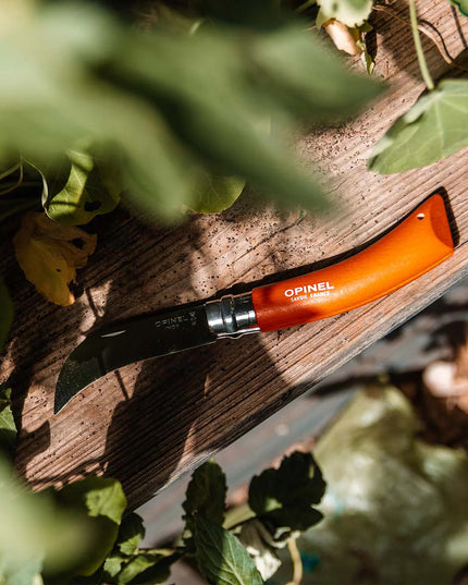 the No. 08 Pruning Knife with orange handle resting on a wooden garden bench