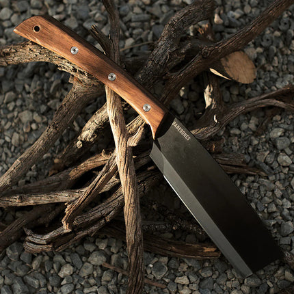 the japanese nata hatchet resting atop a pile of sticks and twigs on stony ground