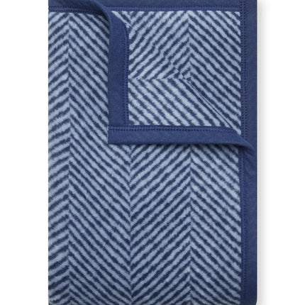 The folded Harborview Herringbone Navy Blanket with the top right corner folded over to show the reverse of the design
