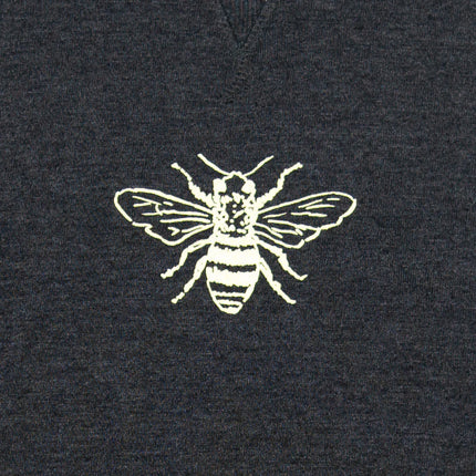 White embroidered bee design on a dark fabric background