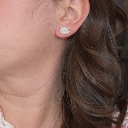 Close-up of a person wearing a silver hydrangea petal-shaped earring.