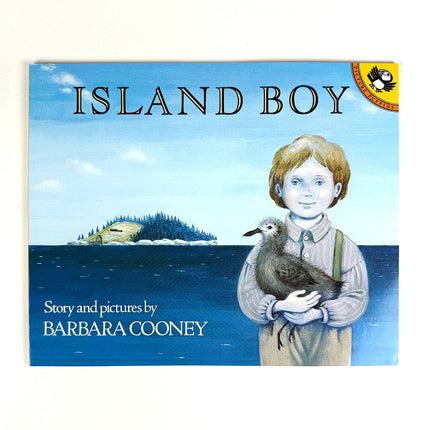 Book cover of 'Island Boy' with a boy holding a bird and an island in the background.