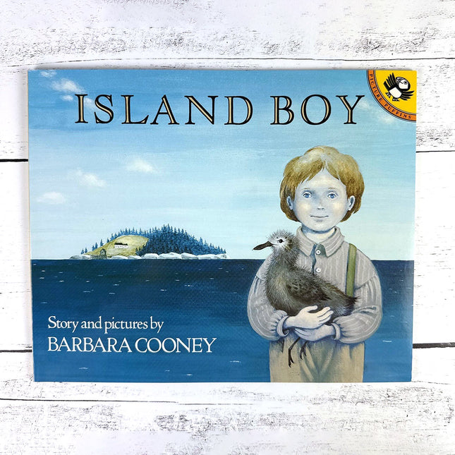 Book cover of 'Island Boy' by Barbara Cooney with a boy holding a bird and an island in the background.