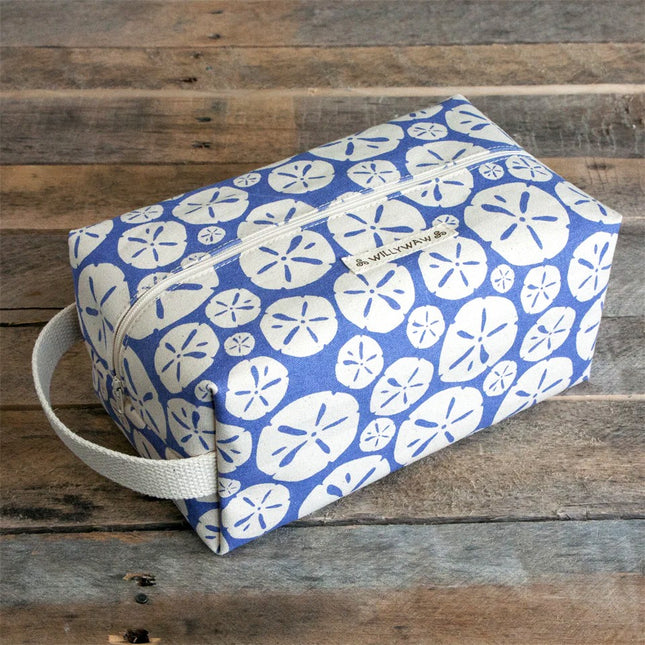 Blue toiletry bag with white sand dollar pattern on a wooden surface