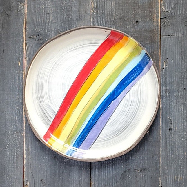 Round ceramic plate with rainbow stripes on a wooden surface