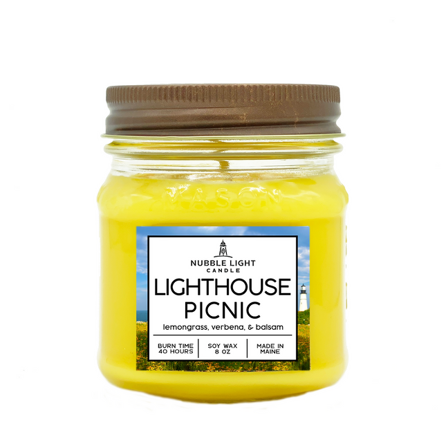 Yellow candle in a glass jar with a brown lid, featuring a 'Nubble Light Candle' label on a white background.