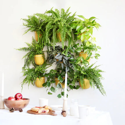Decorative wall with potted plants and a small table with apples and bread.