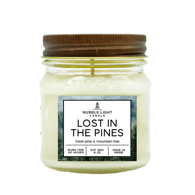 Jar candle labeled 'Lost in the Pines' with a metal lid on a white background