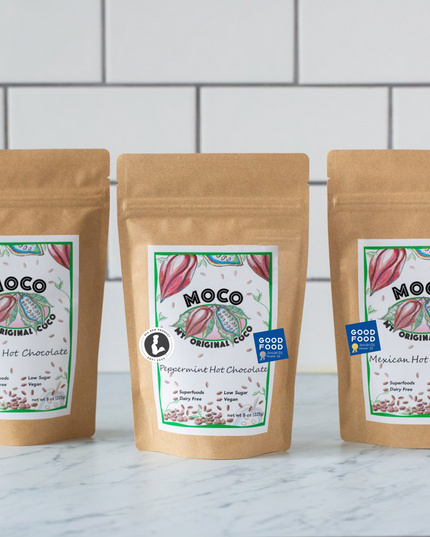 a trio of hot cocoa packages against a white tile background