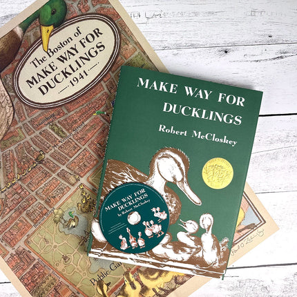 Book titled 'Make Way for Ducklings' by Robert McCloskey on a wooden surface with a map in the background.