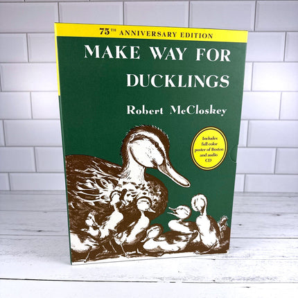 Book titled 'Make Way for Ducklings' by Robert McCloskey on a white wooden surface with a tiled wall background.