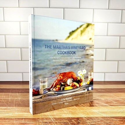 Cookbook titled 'The Martha's Vineyard Cookbook' on a wooden surface with a tiled wall background