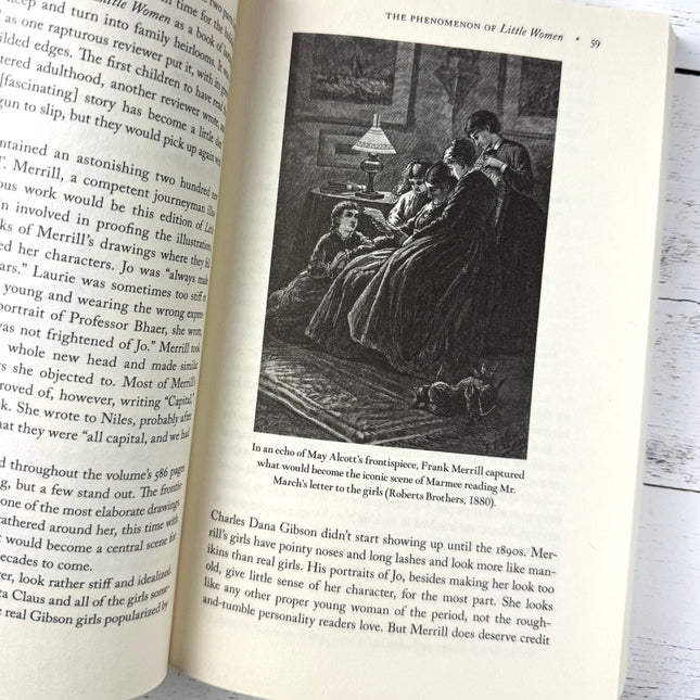 Open book with text and an illustration of a scene from 'Little Women' on a wooden surface.