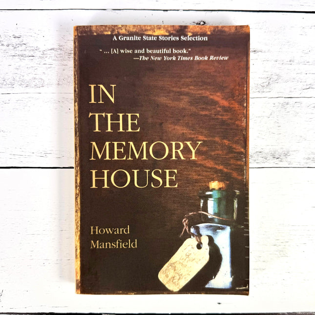 a book titled In the Memory House against a white wood surface