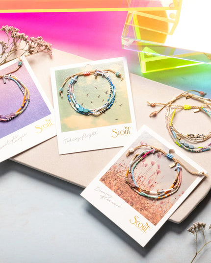 Colorful bracelets on display with cards featuring the brand 'Scout' against a vibrant background.