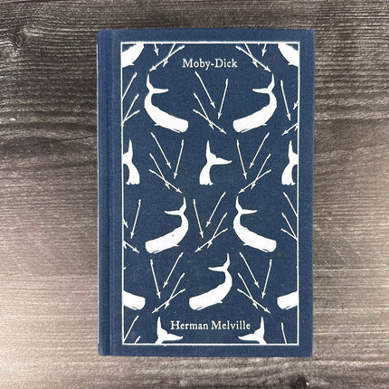 Book titled 'Moby-Dick' by Herman Melville with whale pattern on a wooden surface