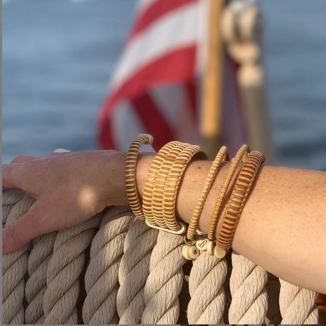 wood bracelets on a wrist with a blurred American flag and boat in the background