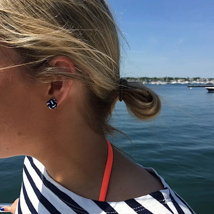 Person wearing a striped shirt with a view of water and boats in the background