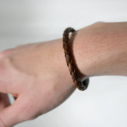 braided moose leather bracelet in a rich, deep brown leather worn on a model's hand showing the slim, yet masculine scale of the bracelet