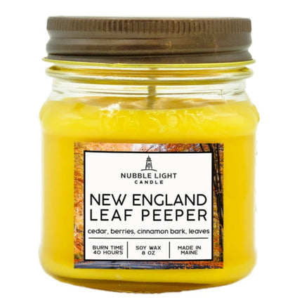 Yellow candle in a glass jar with a brown lid, featuring a label on a white background.