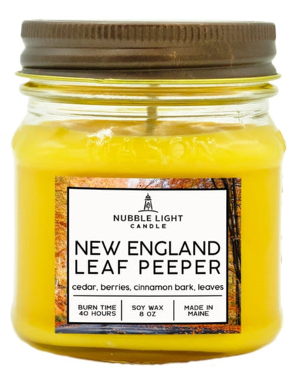 Yellow candle in a glass jar with a brown lid, featuring a label on a white background.