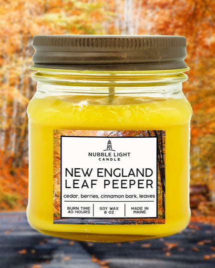 Yellow candle in a mason jar with a label against an autumn leaf background