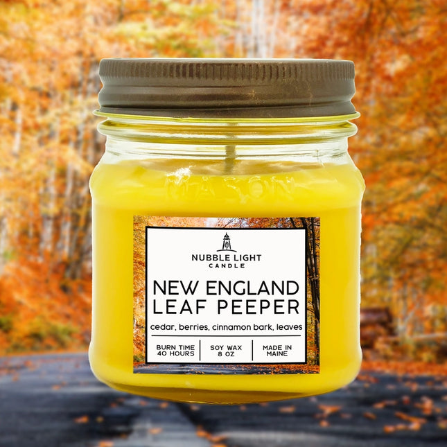 Yellow candle in a mason jar with a label against an autumn leaf background