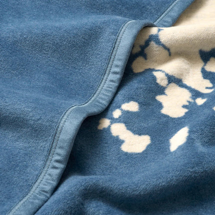 Close-up of a blue fleece blanket with a patterned corner.