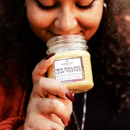 Person holding a jar labeled 'New England Leaf Peeper' close to their face.