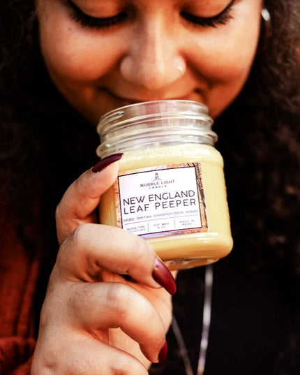 Person holding a jar labeled 'New England Leaf Peeper' close to their face.
