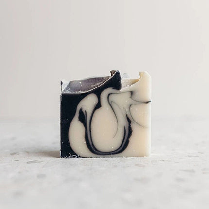 Marble-patterned soap bar with black and white design on a light gray background