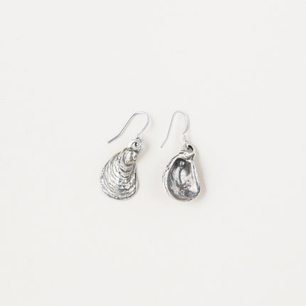 a pair of pewter oyster shell shaped earrings on a white background with one earring showing the backside revealing the inner detail of the shell