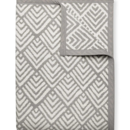 A folded Oyster Cove Diamonds Grey blanket with the top right corner folded over to show the reverse of the design