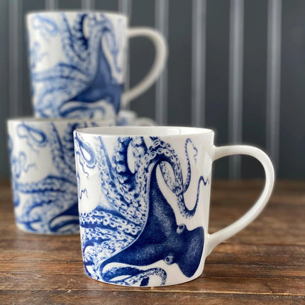 White mugs with blue octopus design on a wooden surface