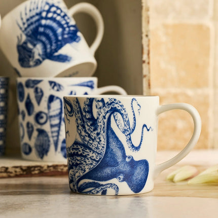 Mugs with blue octopus design on a wooden surface