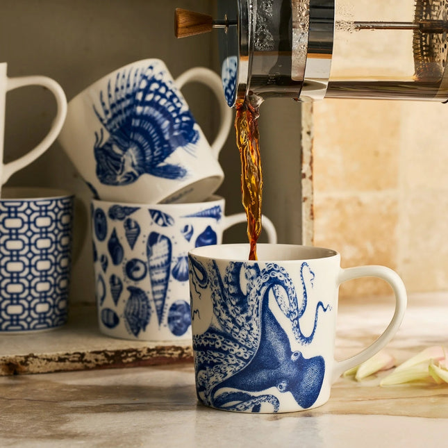 Blue and white patterned mugs with a coffee being poured into one of them.