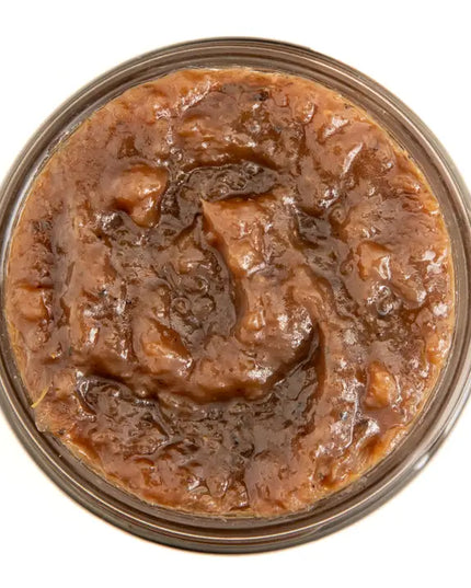 Close-up of a jar of savory caramelized onion jam on a white background