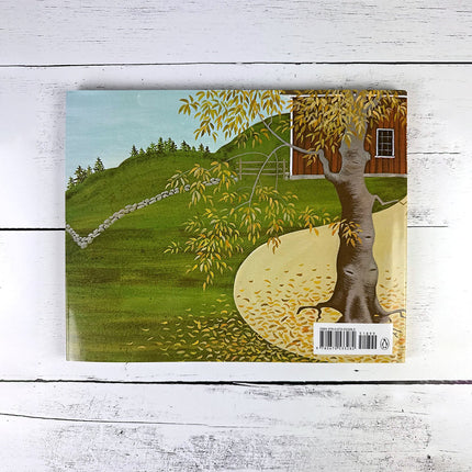 Book cover with a scenic illustration of a tree, house, and landscape on a wooden surface