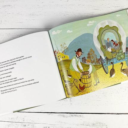 Illustrated book page with a scene of people around a covered wagon on a wooden surface.