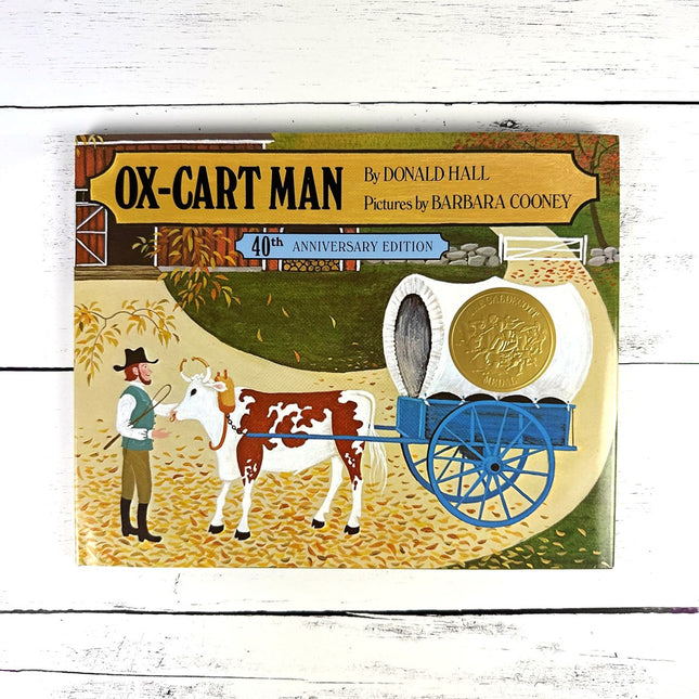 Book cover of 'Ox-Cart Man' with an ox and cart illustration on a wooden surface
