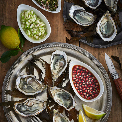 Platter of oysters with garnishes on a wooden table