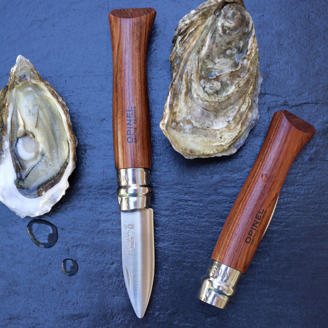 Opinel oyster knife with wooden handle and silver blade on a dark surface with oysters.