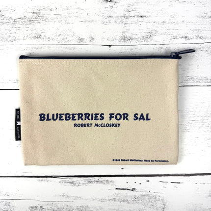 Beige pouch with 'Blueberries for Sal' text on a white wooden surface