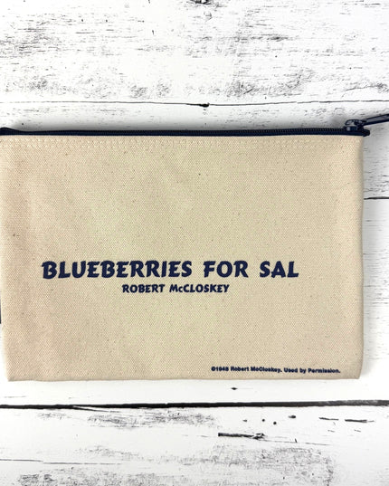 Beige pouch with 'Blueberries for Sal' text on a white wooden surface