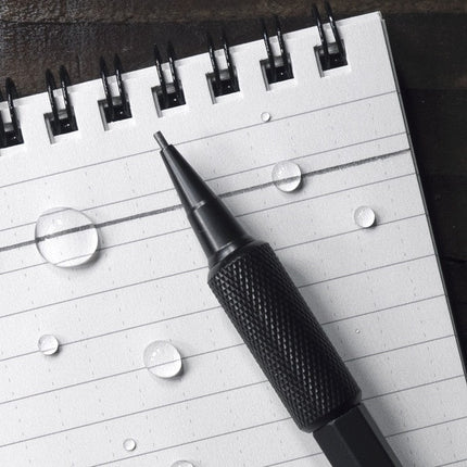 a close up of the mechanical pencil shown atop a weatherproof, spiral bound notepad