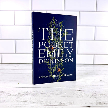 Book titled 'The Pocket Emily Dickinson' on a white wooden surface with a white tiled wall background