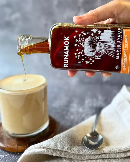Person pouring Runamok maple syrup into a cup of coffee with a blurred background