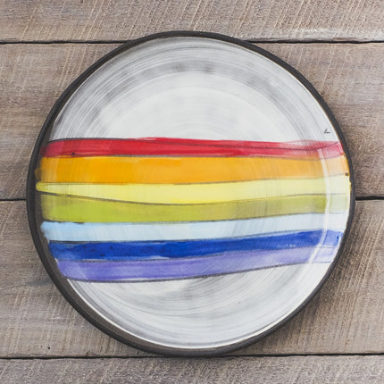 Ceramic plate with rainbow stripes on a wooden surface