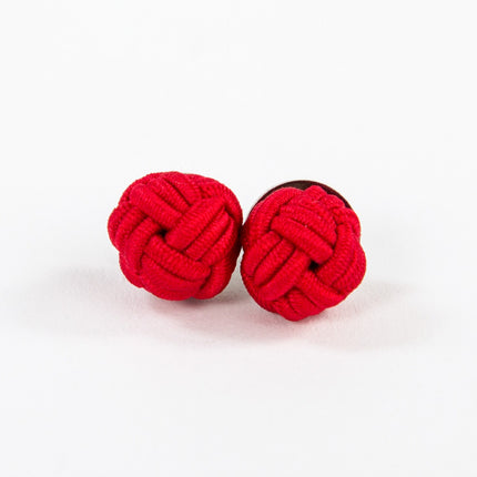 a pair of red monkey fist knot earrings on a white background
