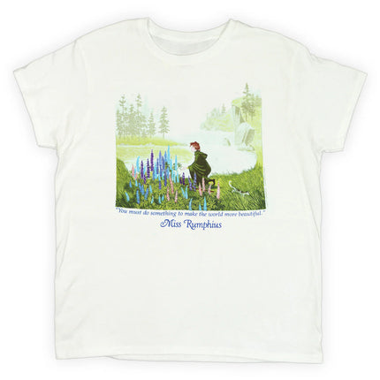 White t-shirt with a book illustration from Miss Rumphius with the title character kneeling to admire a crop of Lupine flowers against a coastal Maine landscape